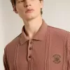 Herrpolo i tegelfärg med broderad logotyp.