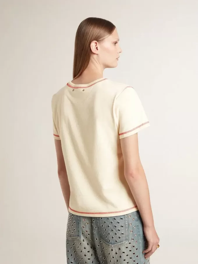 Krämefärgad dam-T-shirt med blekta röda accenter Krämefärgad dam-T-shirt med blekta röda accenter