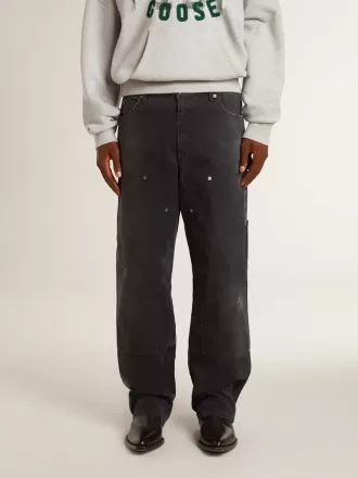 Mansjeans i svart bomull med slitna detaljer och lappar fram