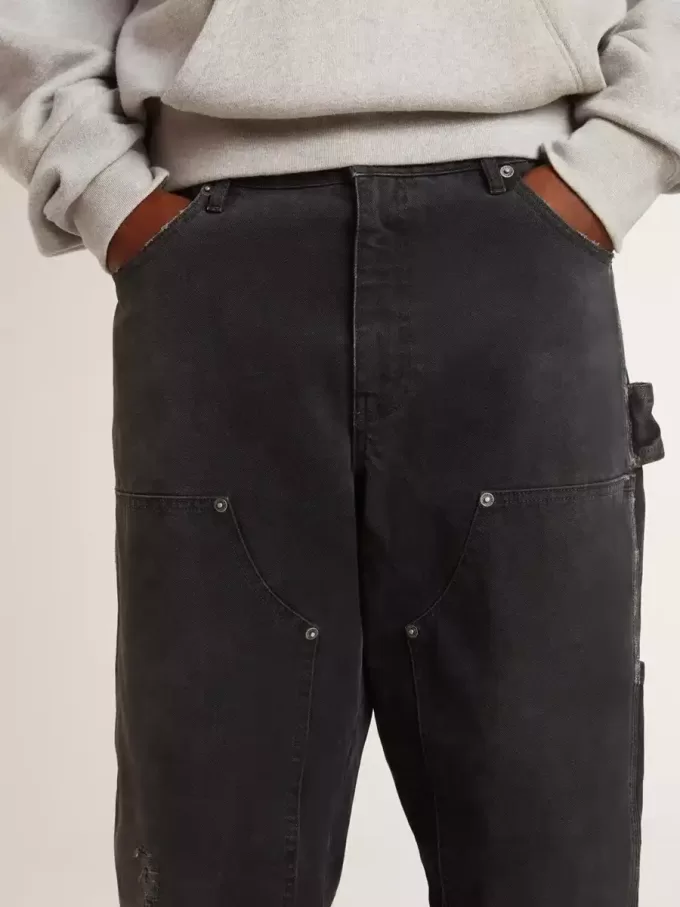 Mansjeans i svart bomull med slitna detaljer och lappar fram