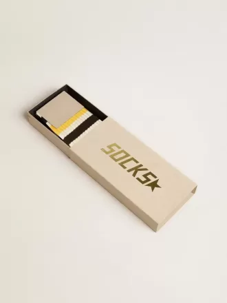 Slitna vita strumpor med slitna detaljer och svarta och gula ränder