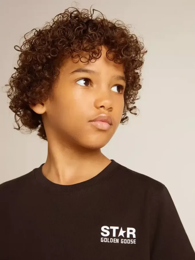Svart T-shirt med kontrasterande vit logotyp på framsidan och maxi-stjärna på baksidan Svart T-shirt med kontrasterande vit logotyp på framsidan och maxi-stjärna på baksidan