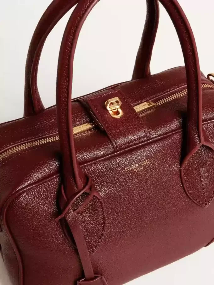Vita Bag i vinrött läder med gulddetaljer Vita Bag i vinrött läder med gulddetaljer