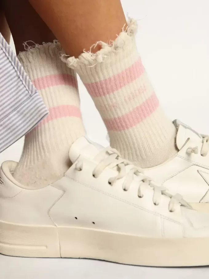 Vita strumpor med slitna detaljer, babyrosa logotyp och ränder